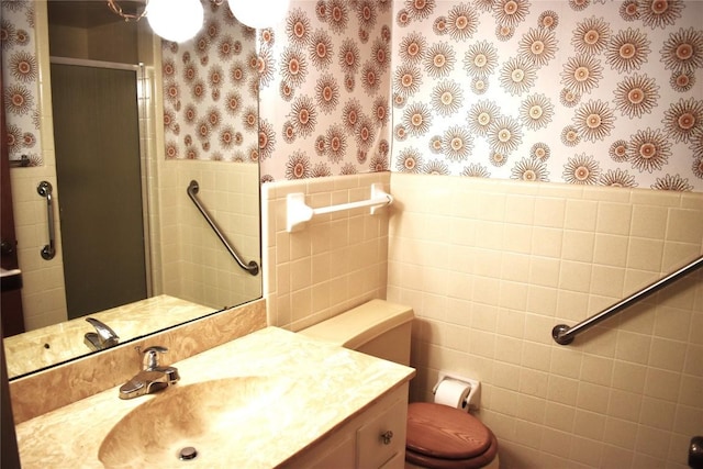 bathroom with tile walls, vanity, a shower with door, and toilet