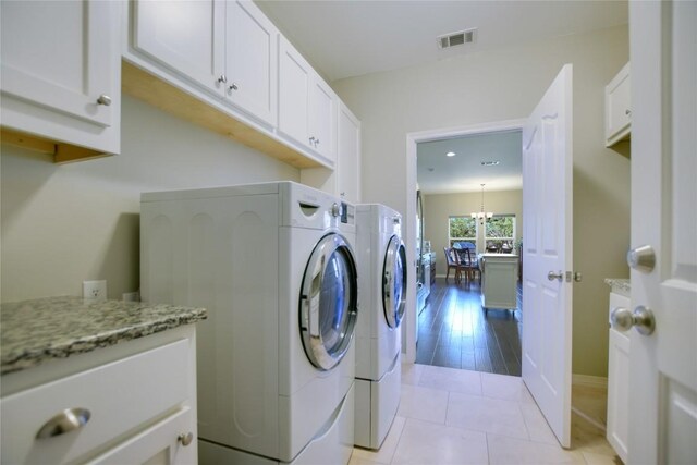 1502 Hi Cir S, Horseshoe Bay, TX 78657 - laundry room featuring washing machine and dryer, cabinet space, light tile patterned floors, baseboards, and a chandelier