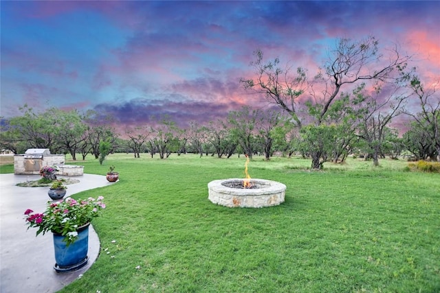 yard at dusk featuring area for grilling, an outdoor fire pit, and a patio area