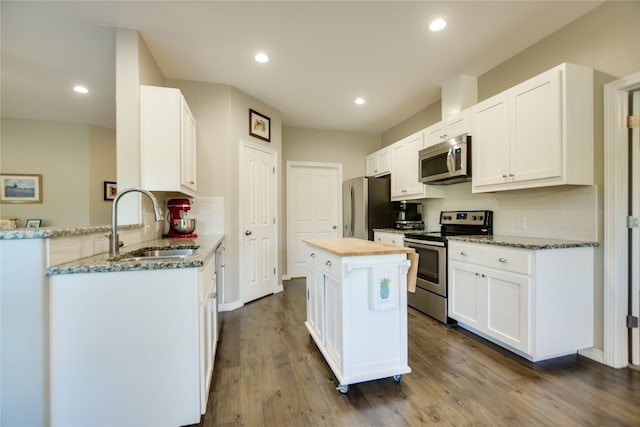 kitchen featuring stainless steel appliances, white cabinets, wood-type flooring, sink, and tasteful backsplash