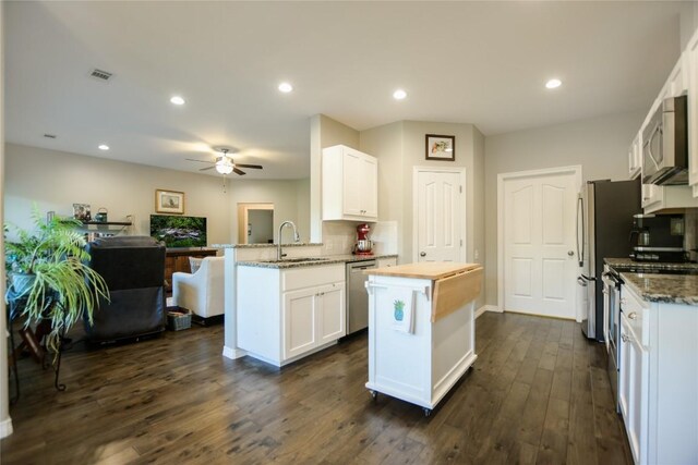 kitchen with stainless steel appliances, white cabinets, ceiling fan, and dark hardwood / wood-style floors