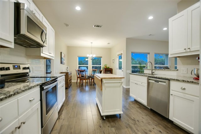 kitchen with a wealth of natural light, backsplash, dark wood-type flooring, and stainless steel appliances