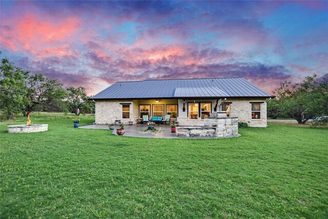 1502 Hi Cir S, Horseshoe Bay, TX 78657 - back of house at dusk featuring stone siding, a patio, ceiling fan, a lawn, and metal roof