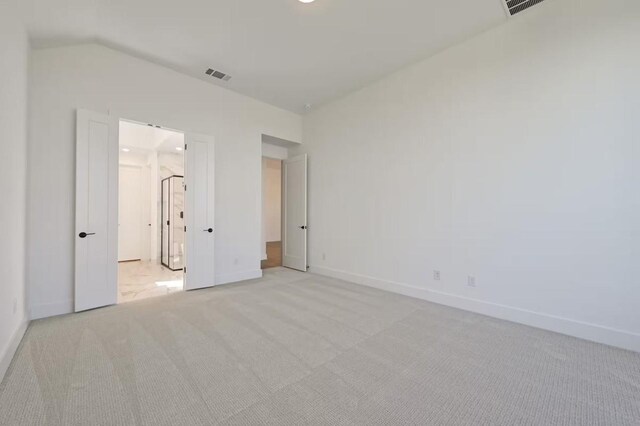 unfurnished bedroom featuring light colored carpet and vaulted ceiling