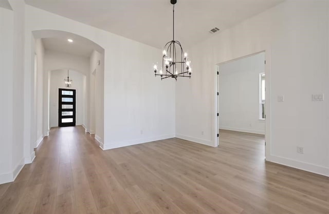 unfurnished dining area with an inviting chandelier and light wood-type flooring