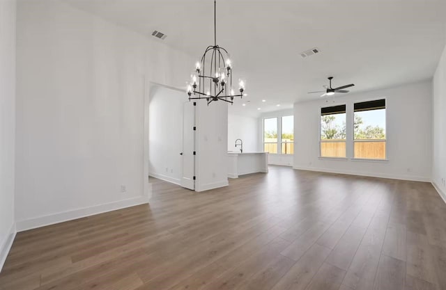 unfurnished living room with sink, ceiling fan with notable chandelier, and hardwood / wood-style flooring