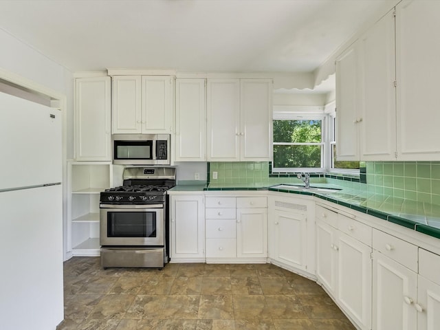 kitchen featuring tile counters, white cabinets, sink, backsplash, and stainless steel appliances