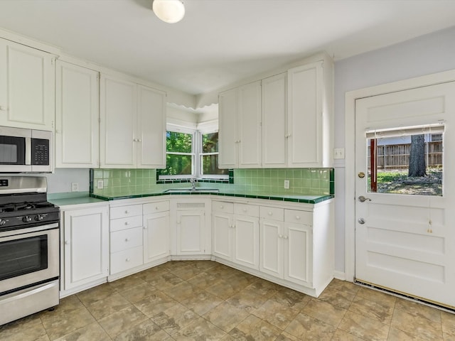 kitchen featuring sink, white cabinets, stainless steel appliances, and tasteful backsplash