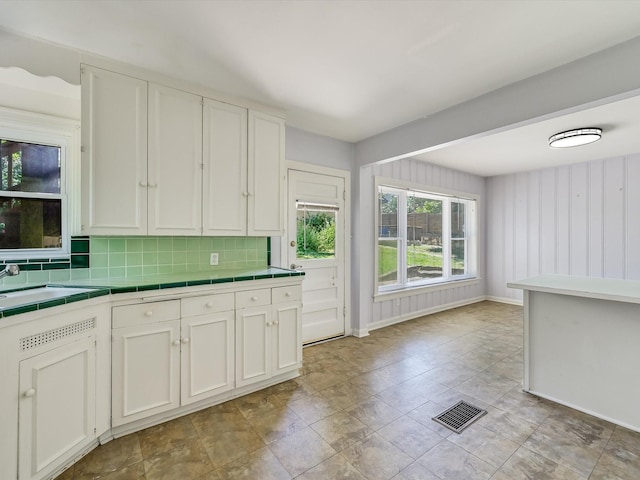 kitchen with sink, backsplash, white cabinets, and tile counters