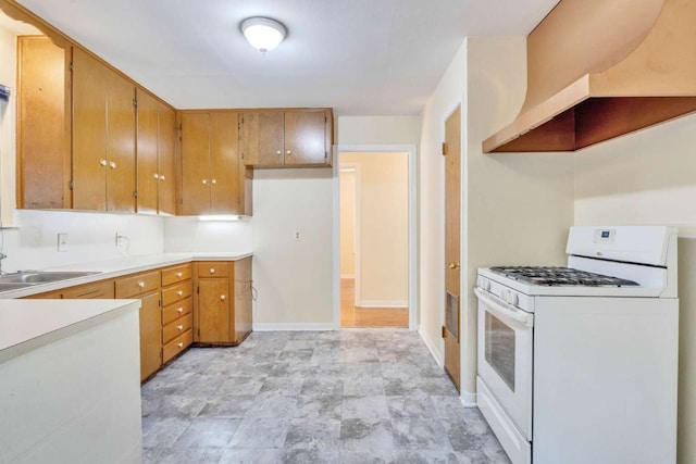 kitchen featuring white range with gas cooktop, ventilation hood, and sink