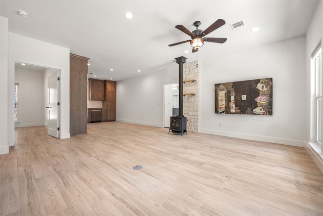 unfurnished living room with light wood-type flooring, a wood stove, visible vents, and recessed lighting