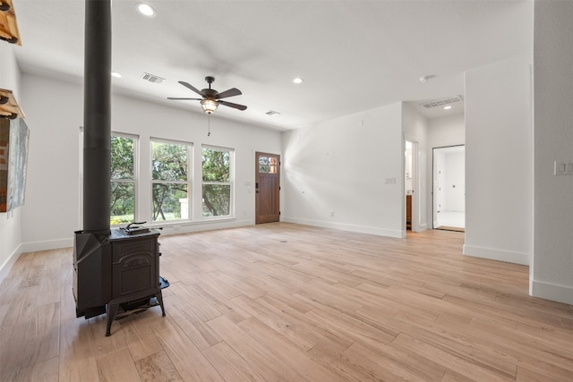 living room featuring a wood stove, light wood finished floors, visible vents, and recessed lighting