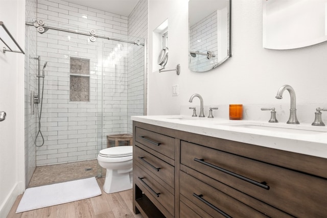 bathroom with double vanity, toilet, a sink, and wood finished floors