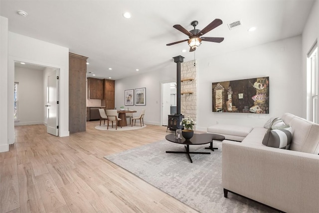 living room with light wood-type flooring, a wood stove, visible vents, and recessed lighting