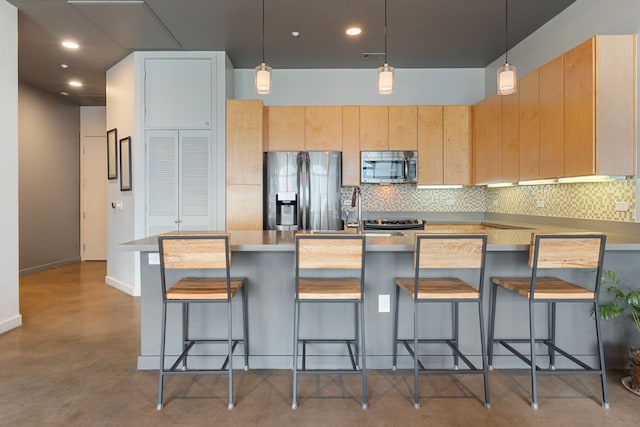 kitchen with appliances with stainless steel finishes, a kitchen breakfast bar, light brown cabinetry, and decorative backsplash