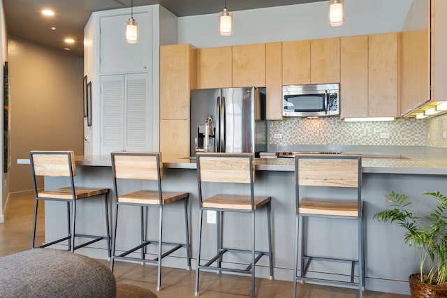 kitchen featuring decorative light fixtures, appliances with stainless steel finishes, backsplash, and light brown cabinets