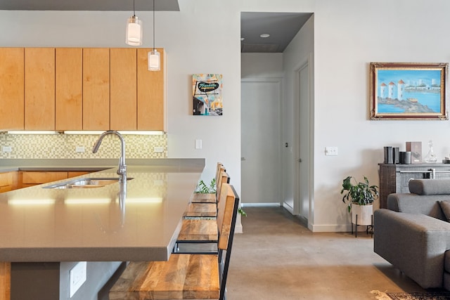 kitchen with kitchen peninsula, pendant lighting, light brown cabinetry, sink, and tasteful backsplash