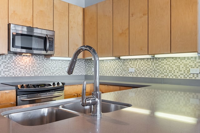 kitchen with sink, decorative backsplash, and appliances with stainless steel finishes