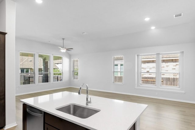 kitchen featuring an island with sink, ceiling fan, light wood-type flooring, lofted ceiling, and sink