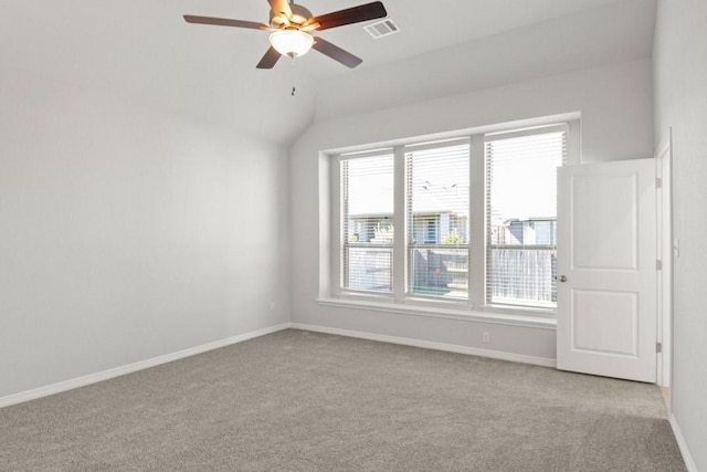 empty room featuring ceiling fan, plenty of natural light, light colored carpet, and lofted ceiling