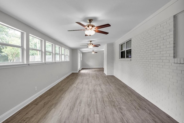 spare room featuring ceiling fan, brick wall, and dark hardwood / wood-style floors