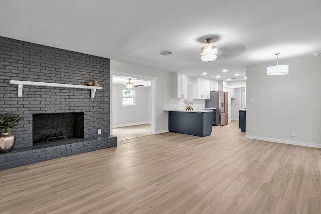 unfurnished living room featuring ceiling fan, light wood-type flooring, and a fireplace