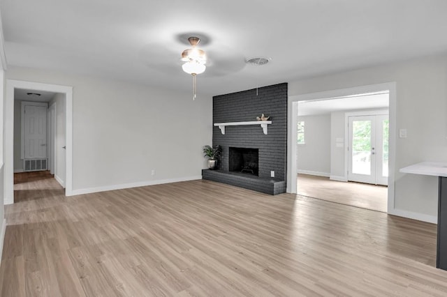 unfurnished living room with light wood-type flooring and a brick fireplace