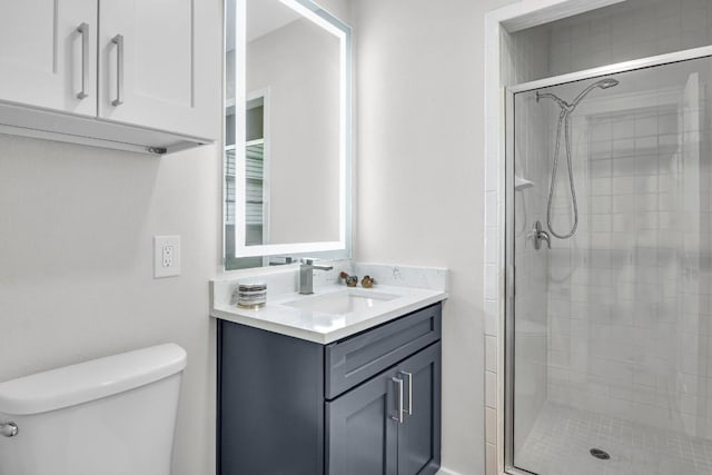 bathroom with vanity, toilet, and a shower with door