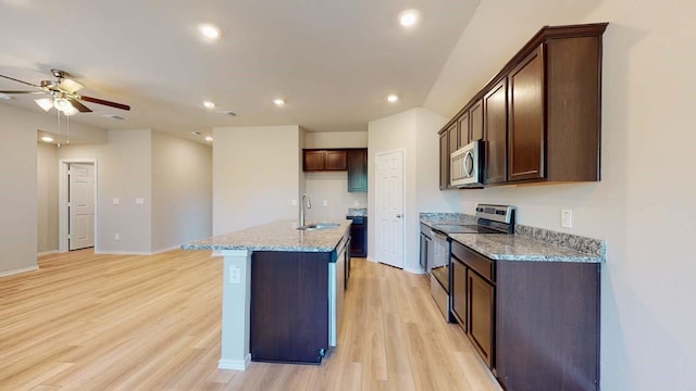 kitchen featuring sink, light stone counters, light hardwood / wood-style flooring, a kitchen island with sink, and appliances with stainless steel finishes