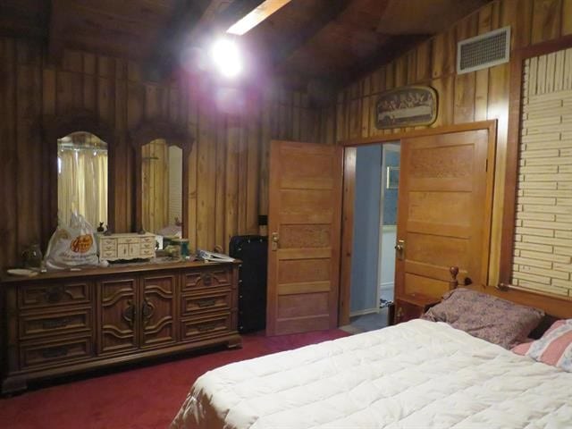 carpeted bedroom with wood walls and lofted ceiling