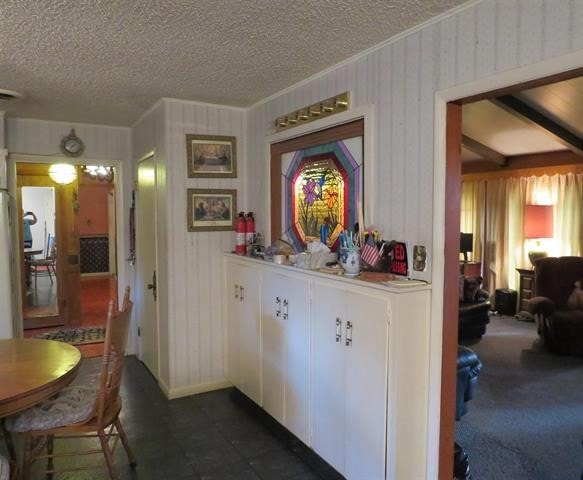 hallway with a textured ceiling and dark carpet