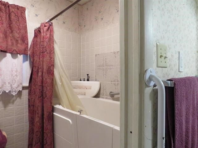 bathroom featuring tile walls and shower / bath combination with curtain