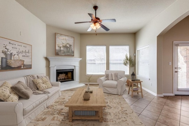 253 Lear Ave, Buda, TX 78610 - living area with a ceiling fan, light tile patterned floors, arched walkways, and a fireplace with raised hearth