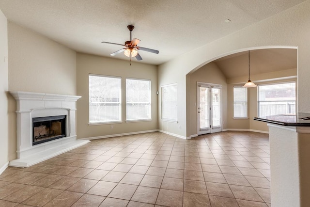 253 Lear Ave, Buda, TX 78610 - unfurnished living room featuring ceiling fan, a fireplace with raised hearth, light tile patterned flooring, and arched walkways