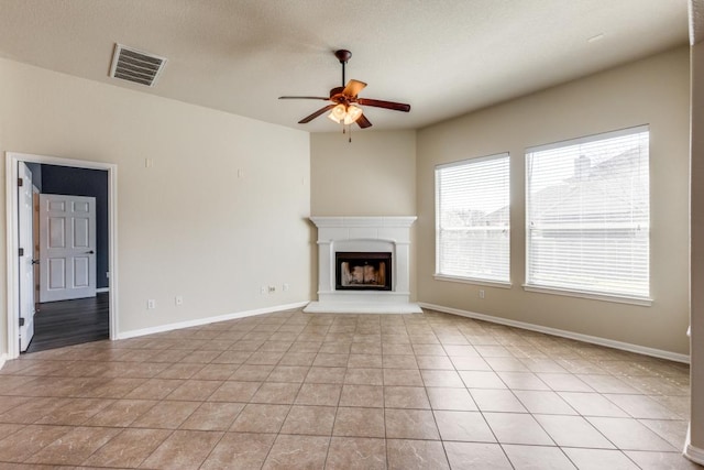 253 Lear Ave, Buda, TX 78610 - unfurnished living room with ceiling fan, healthy amount of natural light, light tile patterned flooring, and a fireplace with raised hearth