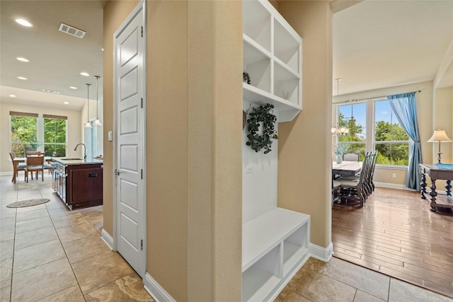 mudroom featuring a sink, visible vents, baseboards, and a healthy amount of sunlight