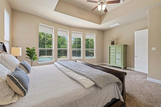 bedroom with visible vents, a tray ceiling, carpet floors, baseboards, and ceiling fan