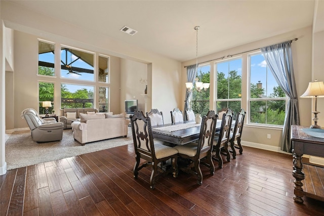 dining space with dark hardwood / wood-style floors, a healthy amount of sunlight, and ceiling fan with notable chandelier