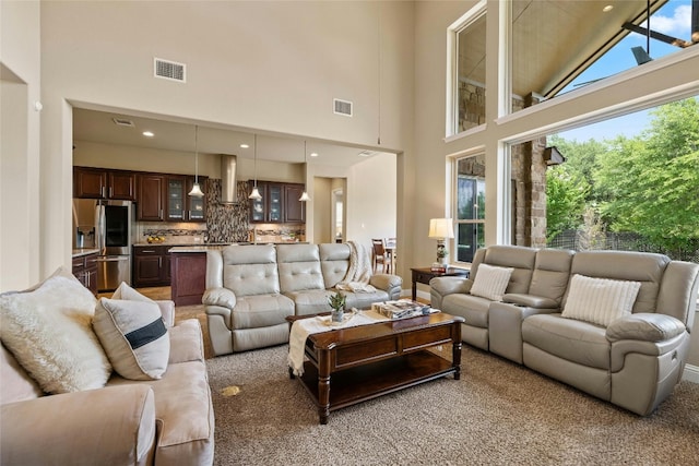 living room with a towering ceiling and light colored carpet