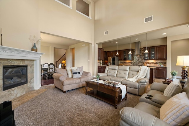 living room with recessed lighting, visible vents, a high end fireplace, and stairway