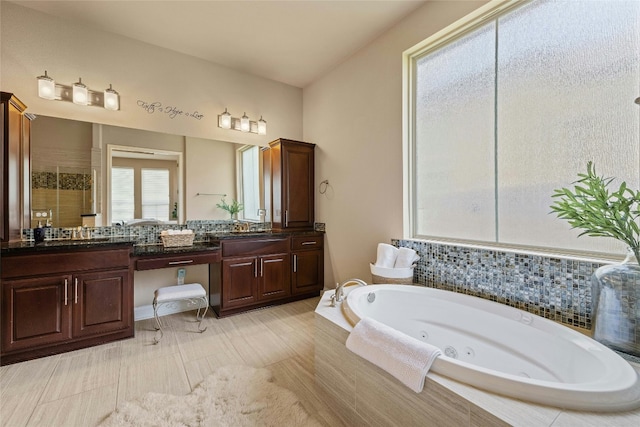 bathroom featuring a tile shower, a jetted tub, and double vanity