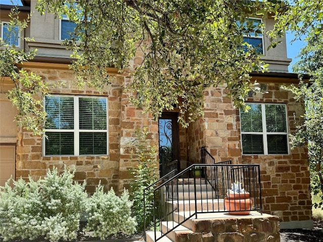 property entrance featuring a garage and stone siding