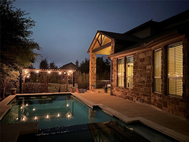 pool at dusk featuring a patio area and a jacuzzi