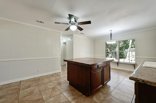 kitchen with crown molding, a kitchen island, and decorative light fixtures