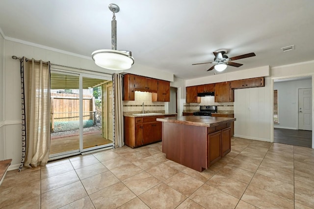 kitchen featuring a center island, sink, ceiling fan, light tile patterned floors, and gas stove