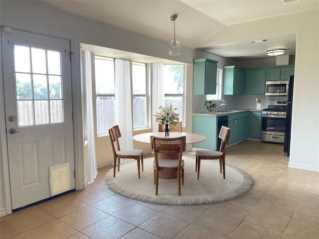 tiled dining area with vaulted ceiling, plenty of natural light, and sink