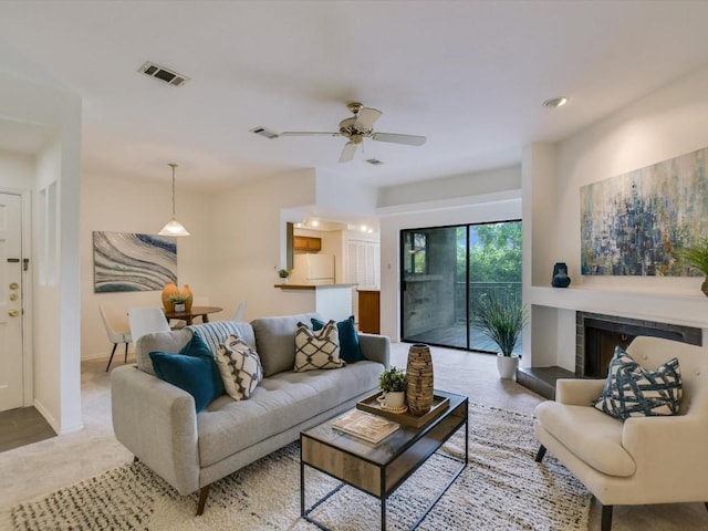 living room with ceiling fan and a tiled fireplace