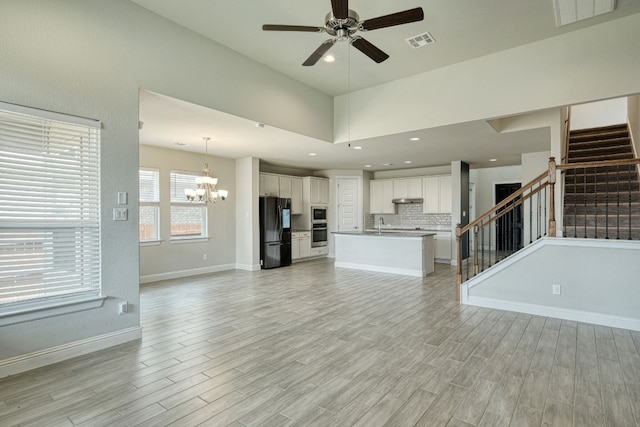 unfurnished living room with sink, ceiling fan with notable chandelier, and light wood-type flooring