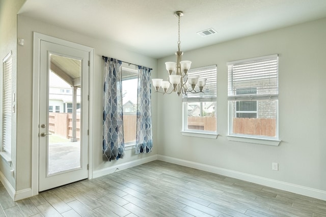 unfurnished dining area featuring light wood-type flooring and a notable chandelier