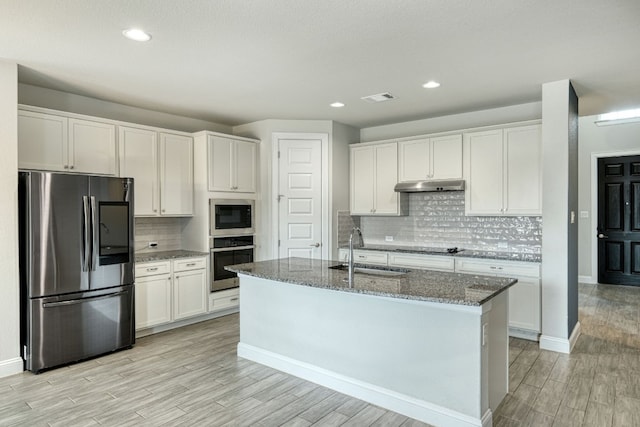 kitchen with white cabinets, stainless steel appliances, stone counters, and sink